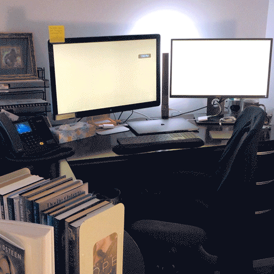 Monitors at a vacant desk displaying a colorful soothing screen saver
