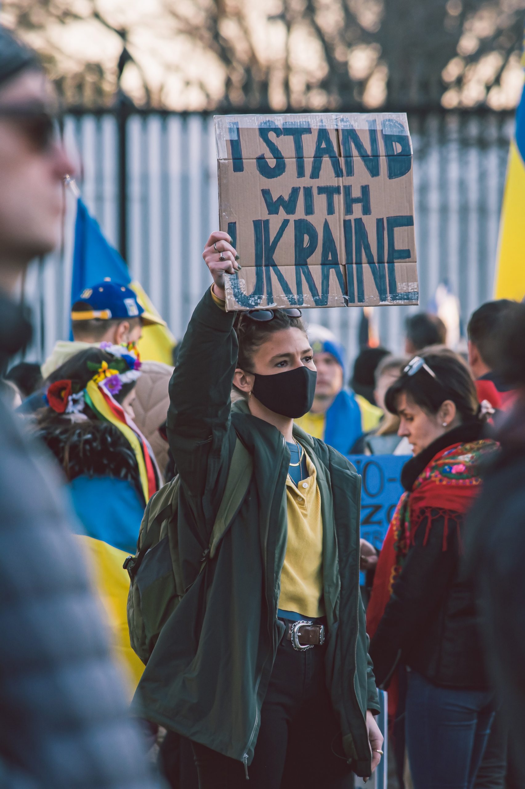 Woman at protest holding sign that says I STAND WITH UKRAINE.