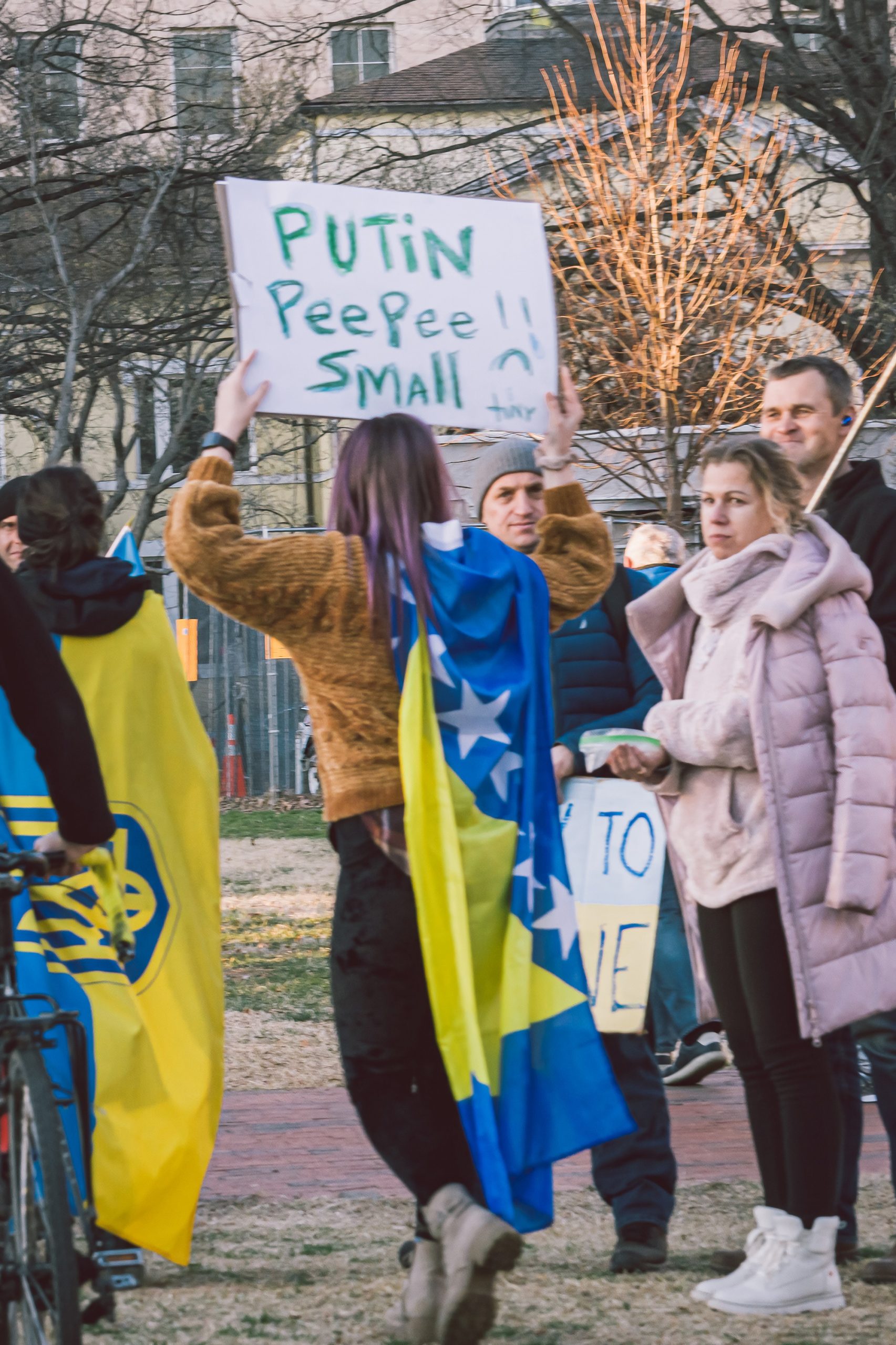 Woman at protest with sign that says PUTIN PEEPEE SMALL.